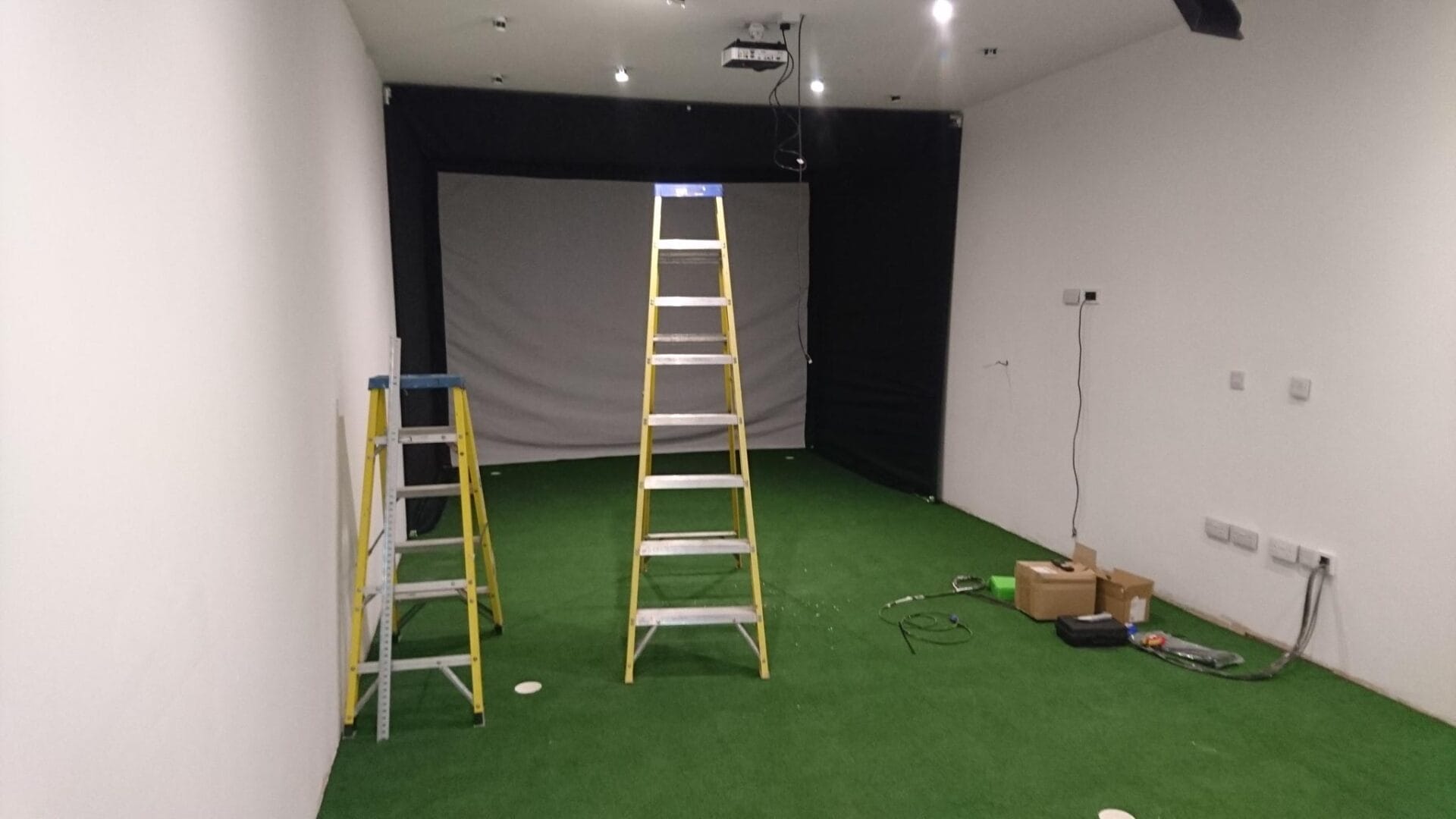 ladders on a green carpet in a room with a black curtain and a black curtain