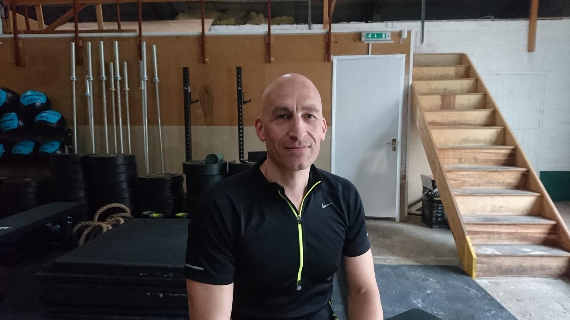 a bald man sitting in a gym